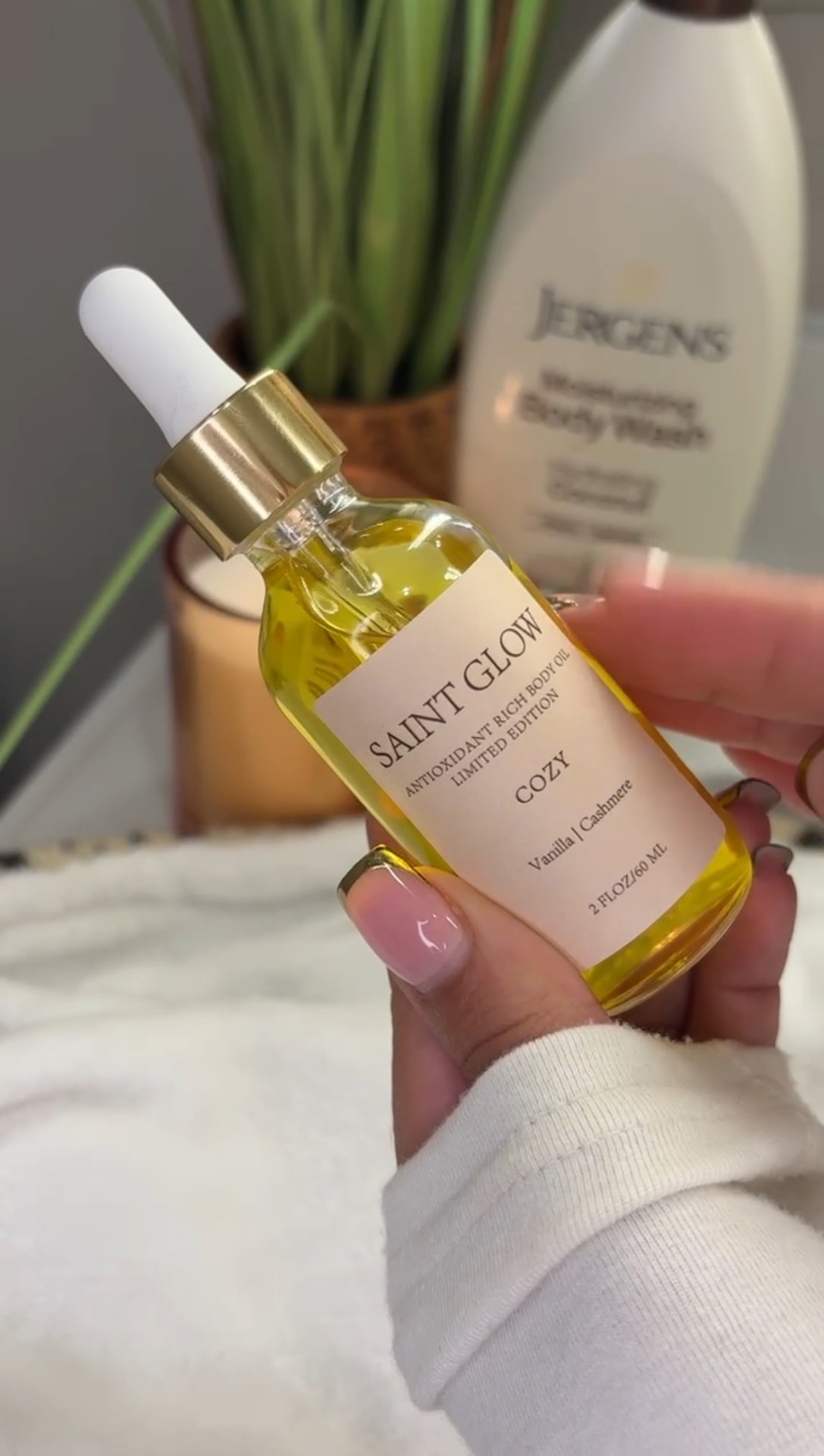 Customer holding the Saint Glow Cozy limited-edition body oil in warm light